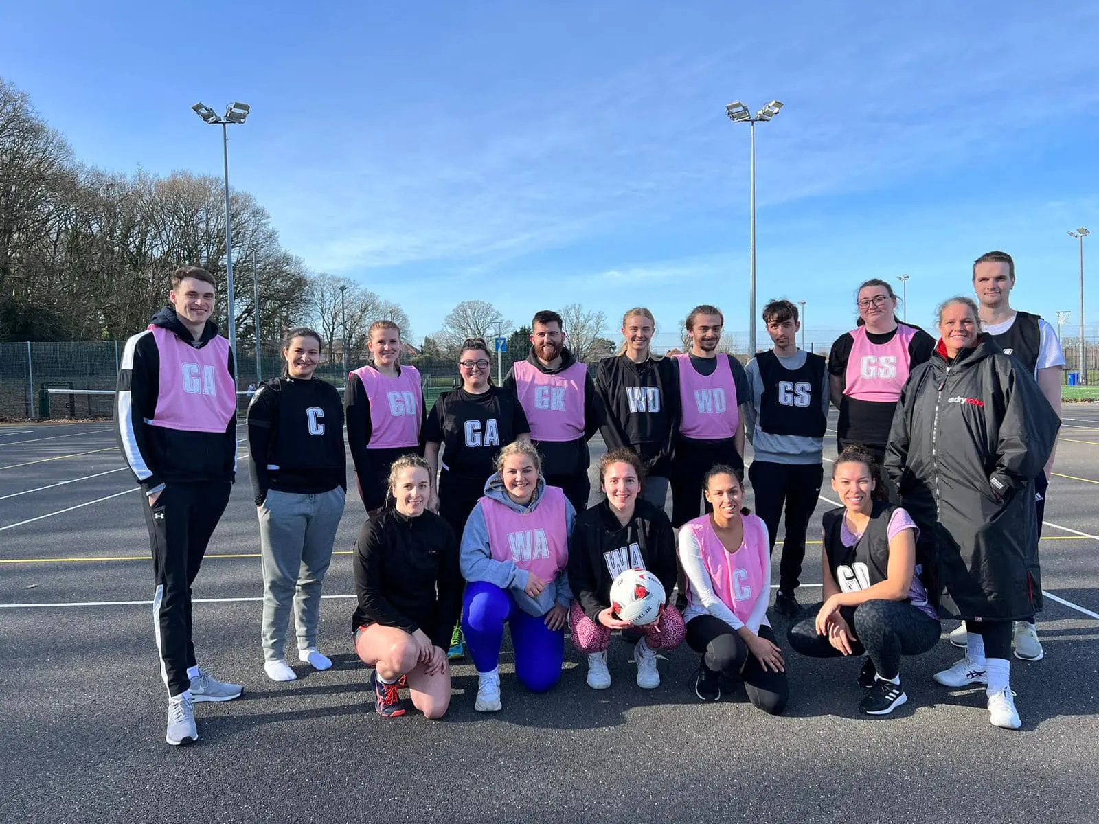 Image of a netball team in yellow bibs posing for a photo